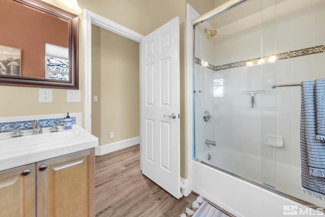 bathroom with vanity, hardwood / wood-style floors, and enclosed tub / shower combo