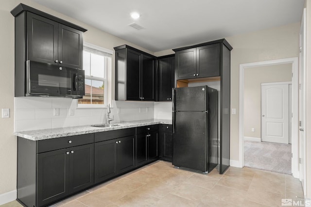 kitchen with sink, decorative backsplash, light stone counters, and black appliances