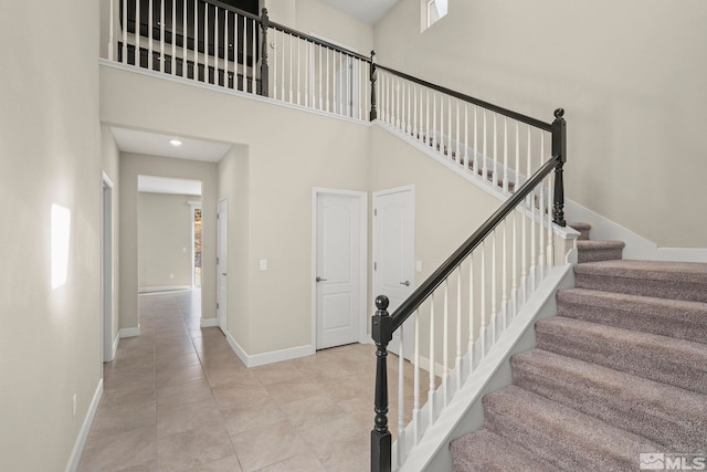 stairs featuring tile patterned flooring and a towering ceiling