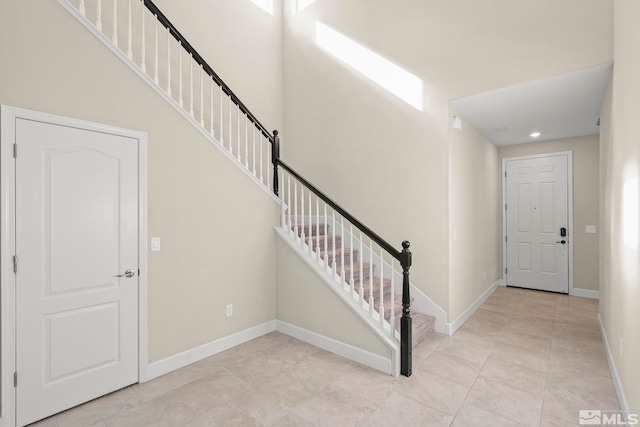 foyer with a towering ceiling and light tile patterned flooring