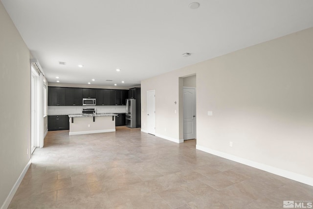 interior space with stainless steel appliances, a kitchen breakfast bar, and an island with sink