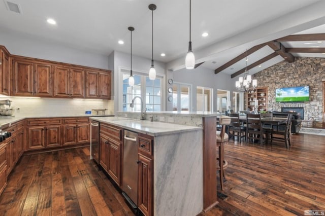 kitchen featuring dishwasher, sink, a breakfast bar area, hanging light fixtures, and a center island with sink