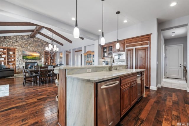 kitchen with stainless steel appliances, an island with sink, sink, and decorative light fixtures