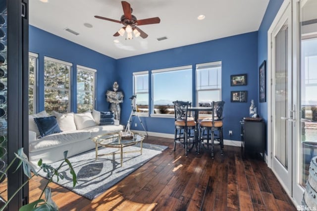 living room featuring dark wood-type flooring, ceiling fan, and plenty of natural light