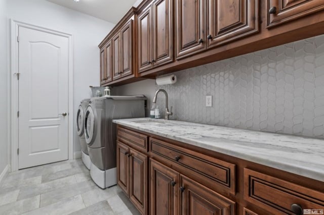 clothes washing area with sink, cabinets, and independent washer and dryer