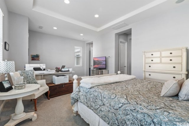 bedroom with a raised ceiling and light colored carpet