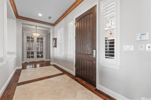 entryway featuring hardwood / wood-style floors, crown molding, and a chandelier