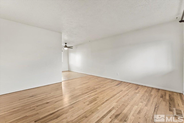 empty room featuring ceiling fan, a textured ceiling, and light wood-type flooring