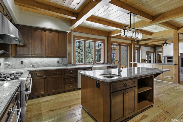 kitchen featuring extractor fan, sink, light stone counters, a center island with sink, and stainless steel appliances