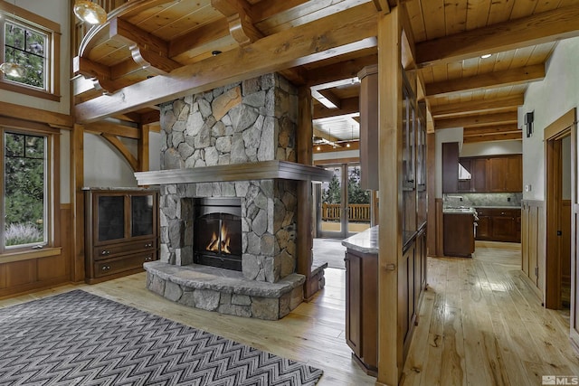 unfurnished living room featuring beam ceiling, wooden ceiling, a fireplace, and light hardwood / wood-style flooring