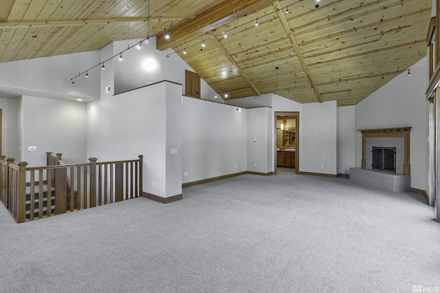 unfurnished living room featuring wood ceiling, light colored carpet, rail lighting, and a brick fireplace