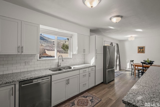 kitchen featuring sink, dark wood-type flooring, appliances with stainless steel finishes, white cabinets, and decorative backsplash