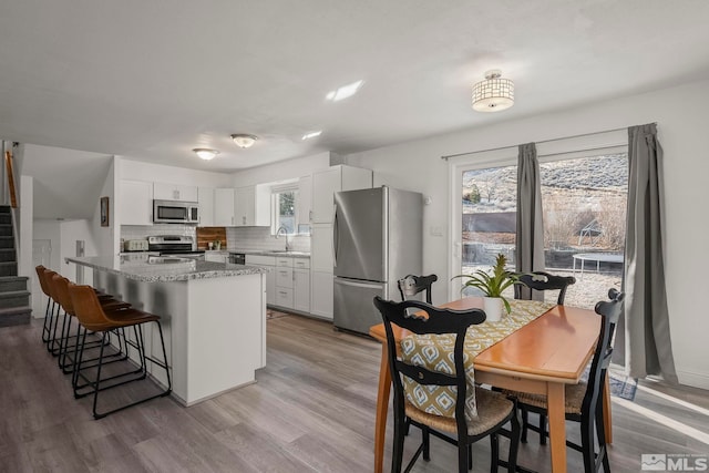 kitchen with white cabinetry, stainless steel appliances, sink, and decorative backsplash