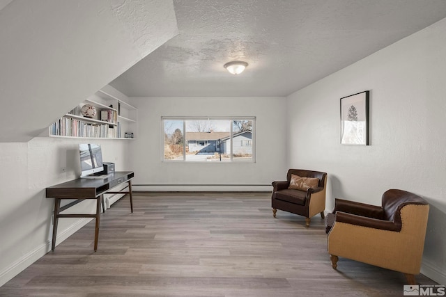 sitting room with baseboard heating, hardwood / wood-style floors, and a textured ceiling