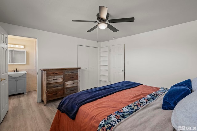 bedroom with connected bathroom, sink, ceiling fan, light wood-type flooring, and a closet