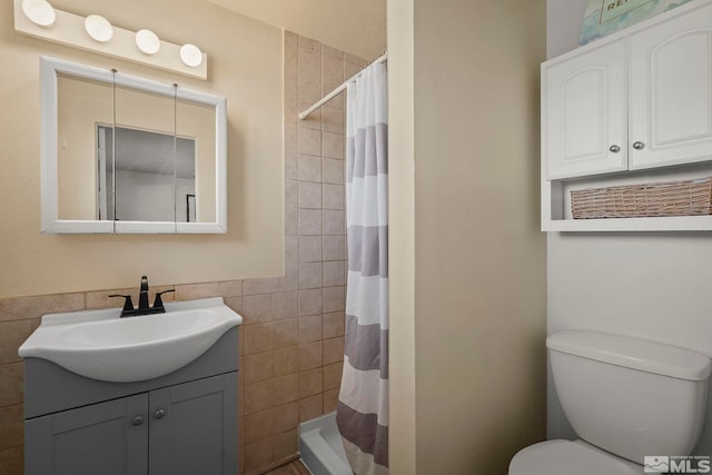 bathroom with vanity, curtained shower, tile walls, and toilet