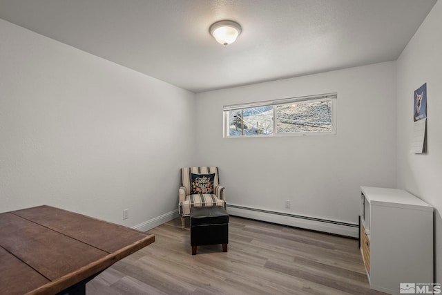 sitting room featuring baseboard heating and light hardwood / wood-style floors