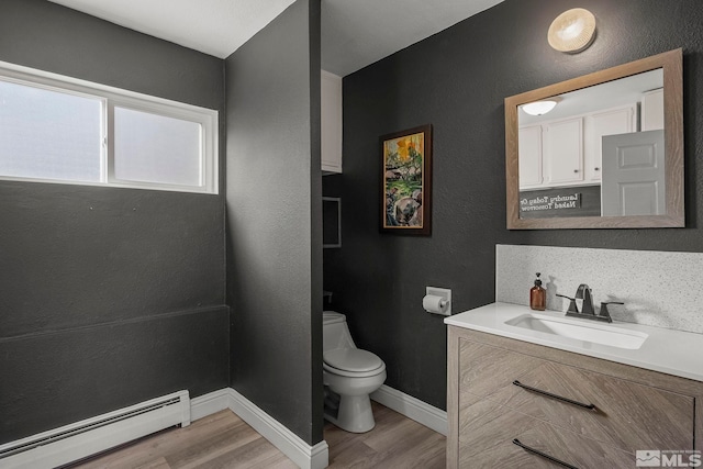 bathroom featuring wood-type flooring, a baseboard heating unit, vanity, and toilet