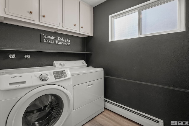 clothes washing area featuring cabinets, a baseboard heating unit, washer and clothes dryer, and light wood-type flooring