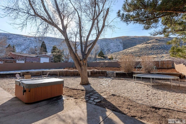 view of yard featuring a hot tub, a mountain view, and a trampoline