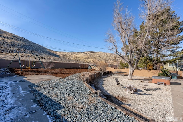 view of yard featuring a hot tub, a mountain view, and a playground