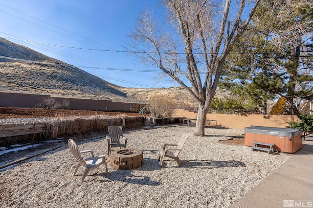 view of yard with a hot tub, a mountain view, and a fire pit