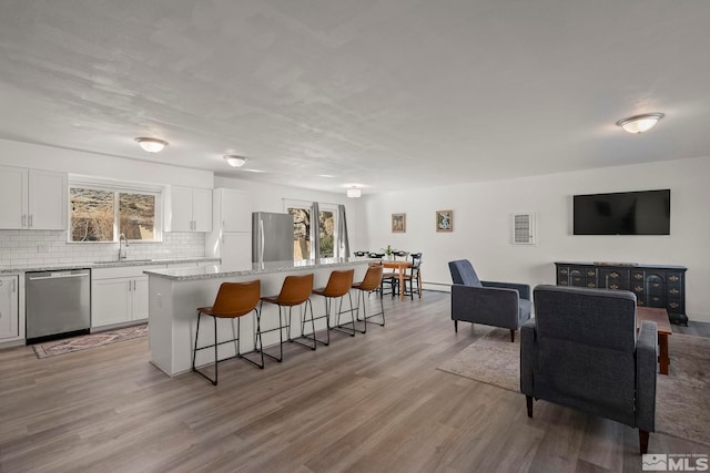 kitchen featuring a kitchen island, appliances with stainless steel finishes, a breakfast bar, white cabinetry, and decorative backsplash