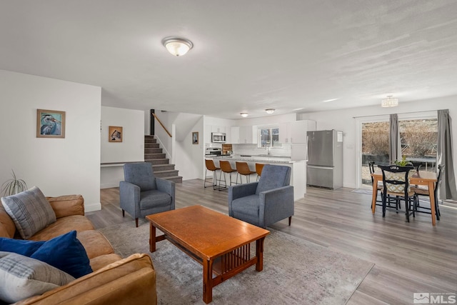 living room featuring sink, light hardwood / wood-style floors, and a healthy amount of sunlight