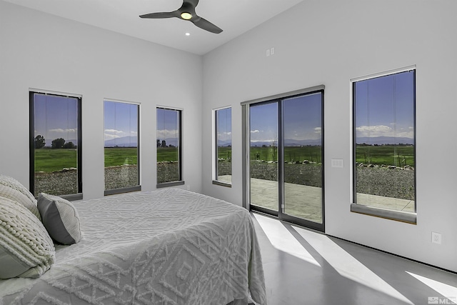 bedroom featuring access to exterior, ceiling fan, and concrete floors