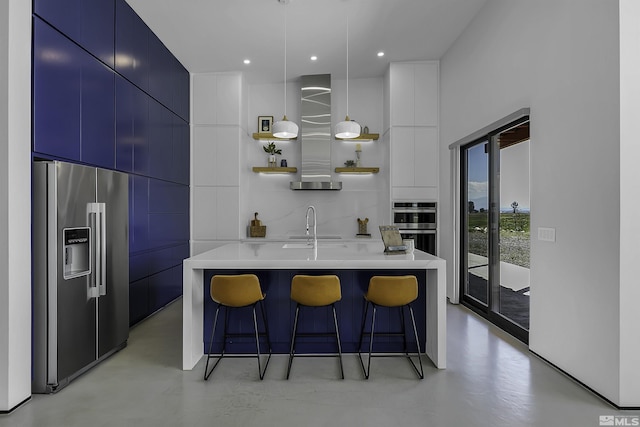 kitchen featuring a kitchen bar, sink, hanging light fixtures, a large island with sink, and appliances with stainless steel finishes