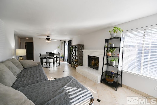 tiled living room with ceiling fan and a brick fireplace