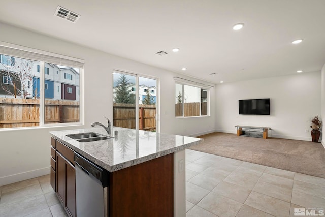 kitchen with sink, light stone counters, dishwasher, an island with sink, and light colored carpet