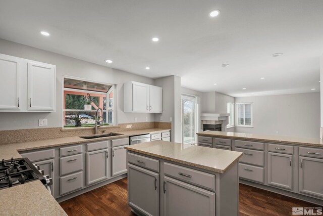 kitchen featuring sink, appliances with stainless steel finishes, gray cabinetry, a kitchen island, and dark hardwood / wood-style flooring