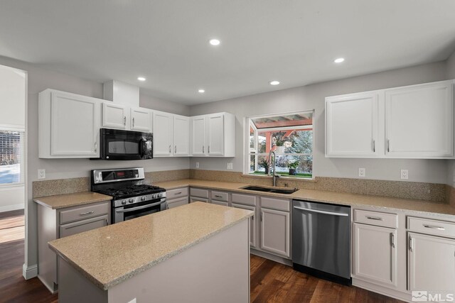 kitchen featuring sink, a center island, appliances with stainless steel finishes, dark hardwood / wood-style flooring, and white cabinets