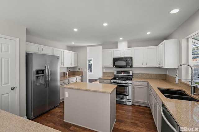 kitchen with sink, light stone counters, a center island, stainless steel appliances, and white cabinets