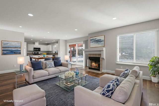 living room featuring a tile fireplace and dark hardwood / wood-style floors