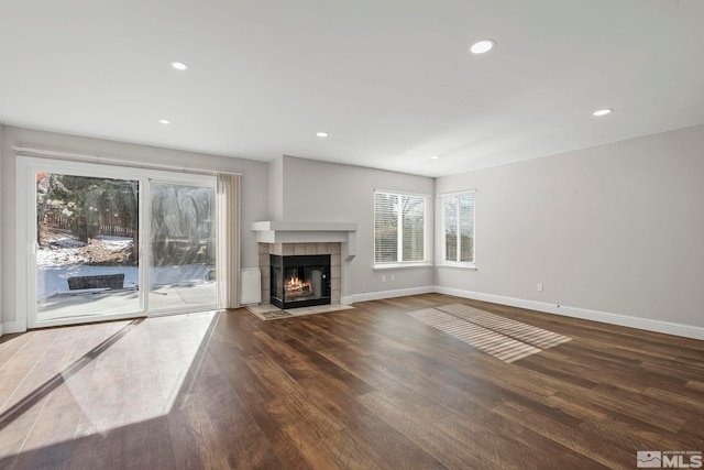 unfurnished living room featuring dark wood-type flooring and a tile fireplace