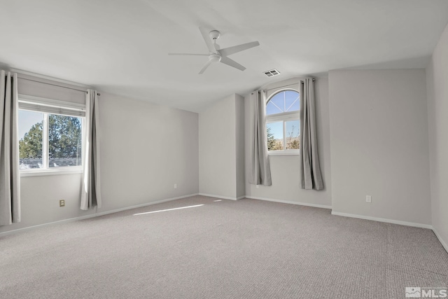 unfurnished room featuring vaulted ceiling, light carpet, and a wealth of natural light