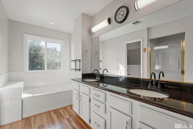 bathroom with wood-type flooring, vanity, and a tub to relax in