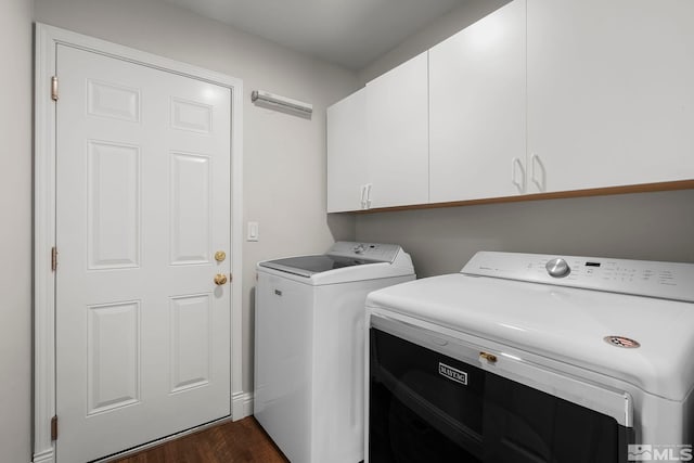 clothes washing area with cabinets, washing machine and clothes dryer, and dark hardwood / wood-style flooring