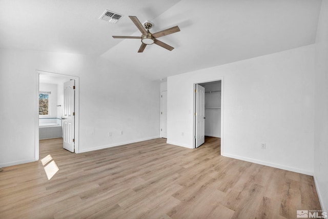 unfurnished bedroom with lofted ceiling, ensuite bath, a spacious closet, light hardwood / wood-style flooring, and ceiling fan