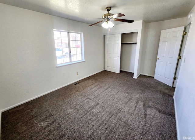unfurnished bedroom featuring ceiling fan, dark carpet, a closet, and a textured ceiling