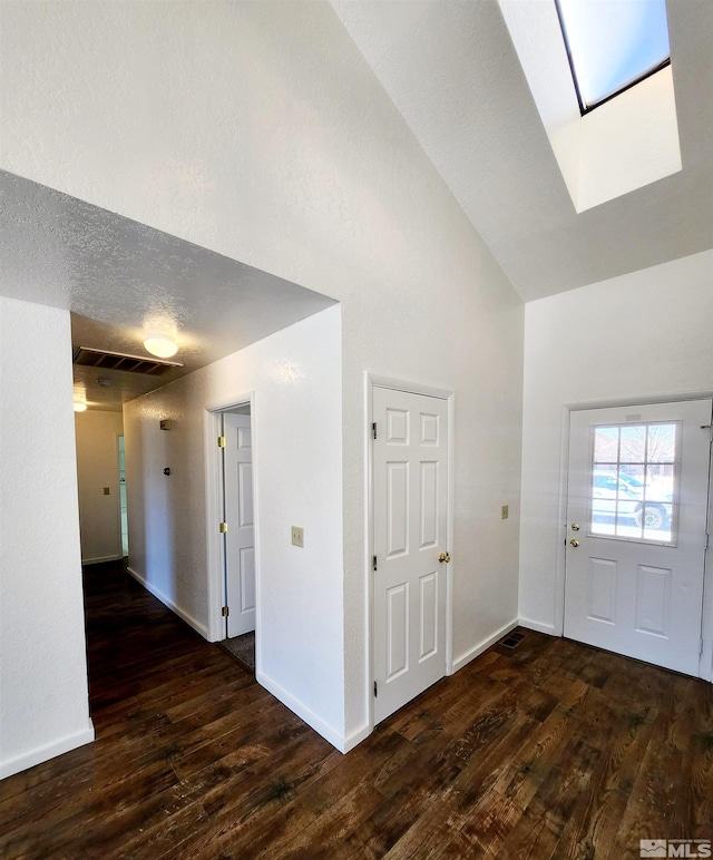 entryway with a skylight, dark wood-type flooring, high vaulted ceiling, and a textured ceiling