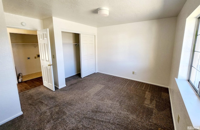 unfurnished bedroom featuring dark carpet, a closet, and a textured ceiling