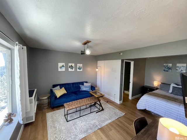 bedroom featuring a textured ceiling, baseboards, and wood finished floors