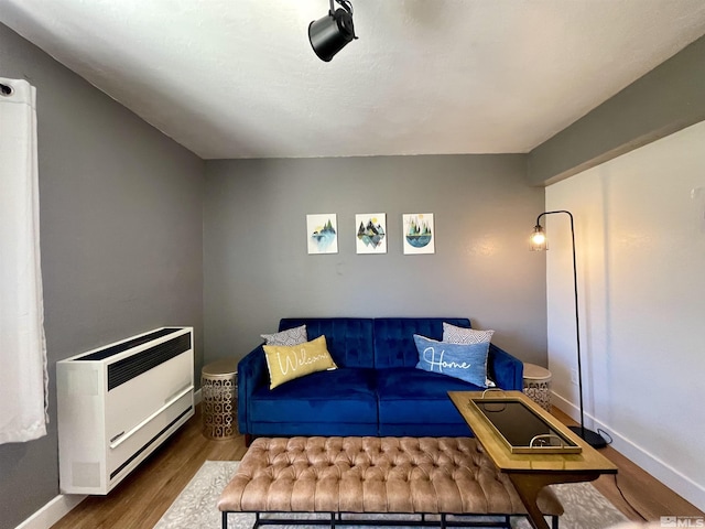 living room featuring baseboards, wood finished floors, and heating unit