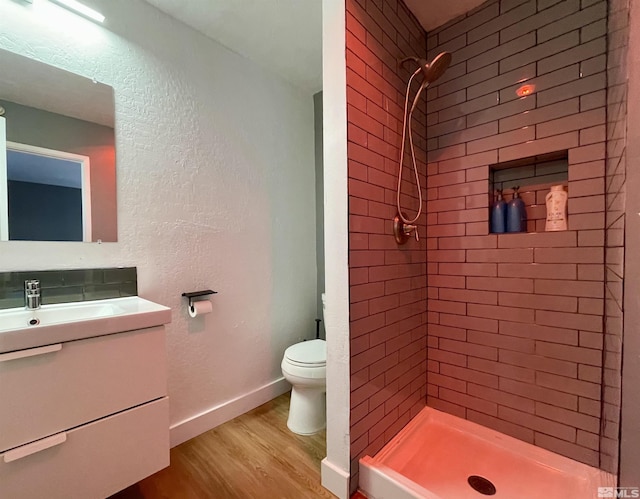 full bath with a stall shower, baseboards, toilet, wood finished floors, and vanity