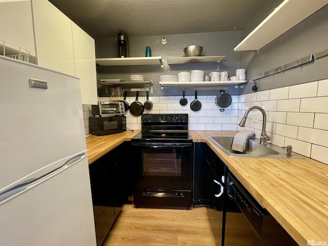 kitchen featuring black appliances, butcher block countertops, open shelves, and a sink