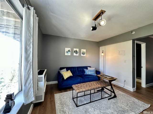 living room featuring dark wood finished floors, a textured ceiling, and baseboards