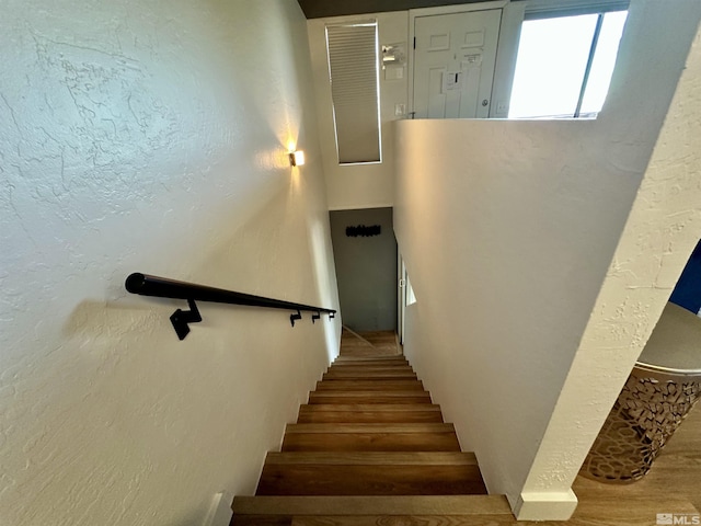 stairway featuring a textured wall and wood finished floors